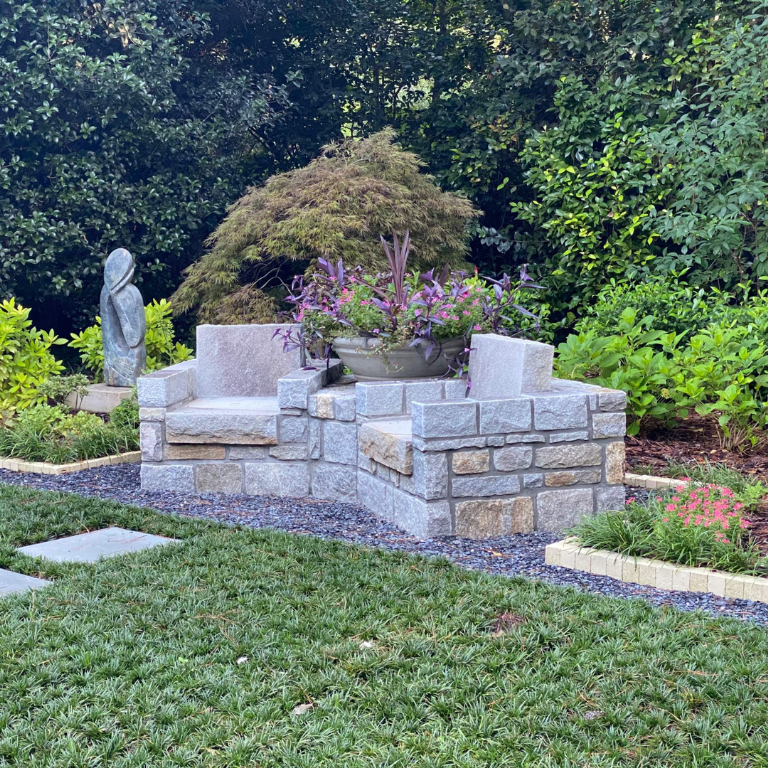 Granite garden bench seating area surrounded by landscaping and stone edging