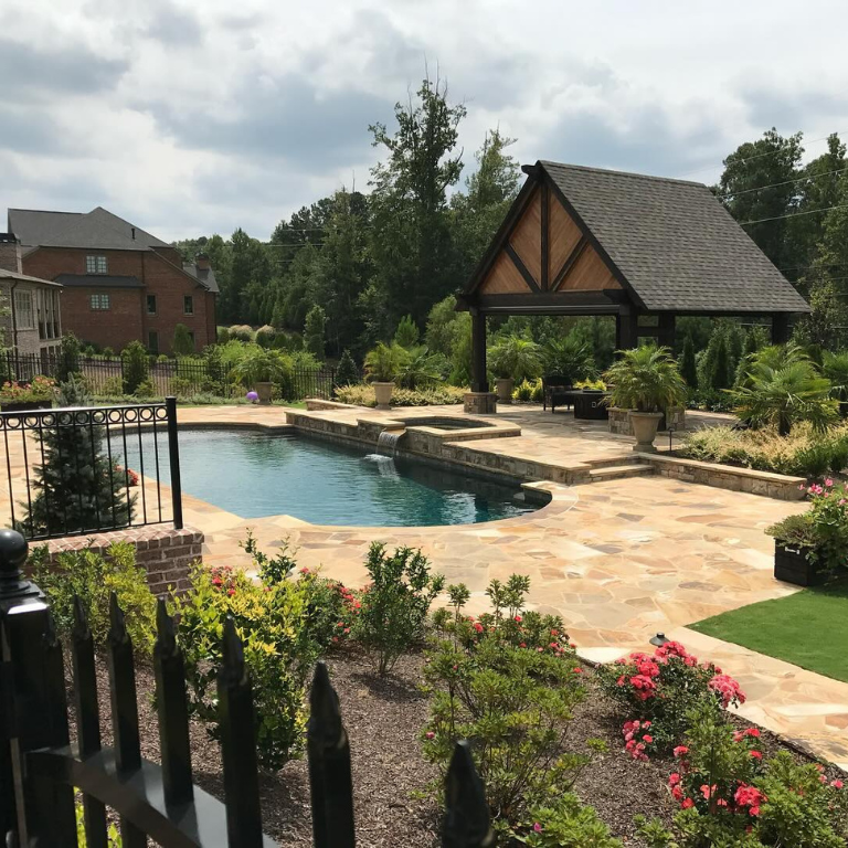 Custom pool and patio with flagstone deck, pavilion, and landscaped backyard